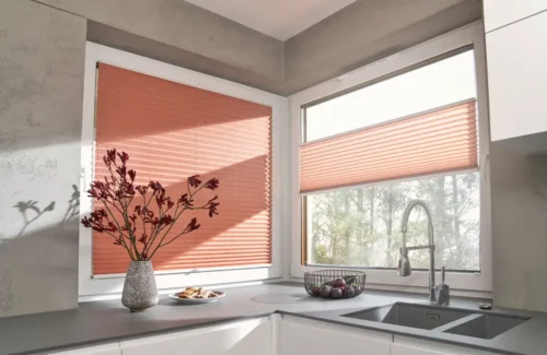 Moderne Küche mit orangefarbenen Plissees an den Fenstern