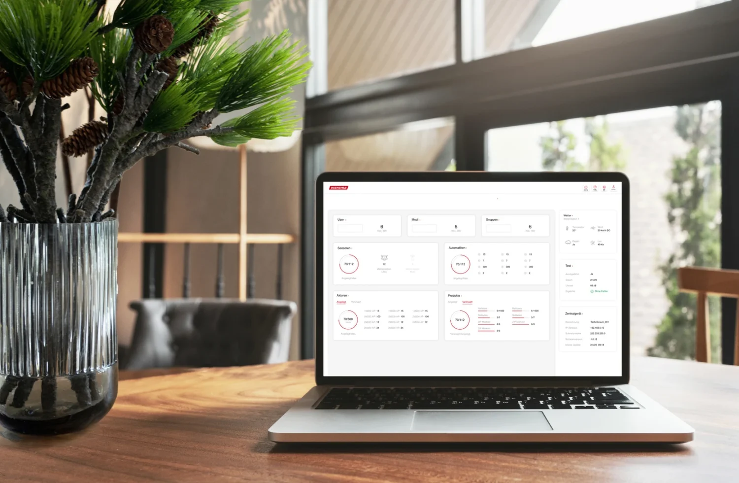 Laptop mit Dashboard-Anzeige auf einem Tisch neben einer Vase